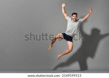 Surprised caucasian man in sleepwear jumping and raising fists on gray isolated background in studio with copy space Royalty-Free Stock Photo #2149599513