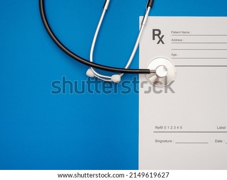 Top view of a stethoscope over the medical prescription sheet on a blue background. Space for text. Medical and healthcare concept