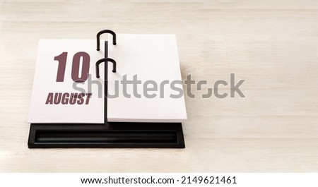 august 10. 10th day of month, calendar date. Stand for desktop calendar on beige wooden background. Concept of day of year, time planner, summer month.