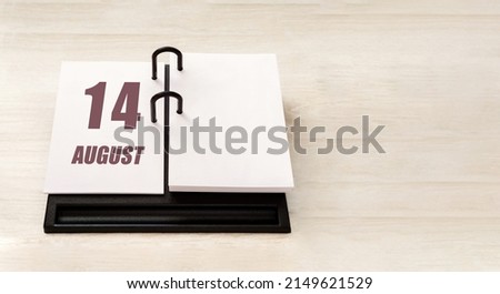 august 14. 14th day of month, calendar date. Stand for desktop calendar on beige wooden background. Concept of day of year, time planner, summer month.