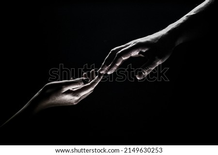 Hands gesturing on black background. Giving a helping hand. Support and help, salvation. Hands of two people at the time of rescue. Romantic touch with fingers, love. Hand creation of adam. Royalty-Free Stock Photo #2149630253