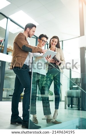 This report looks great. Shot of a group of colleagues talking together over a digital tablet while standing in a large modern office. Royalty-Free Stock Photo #2149634195