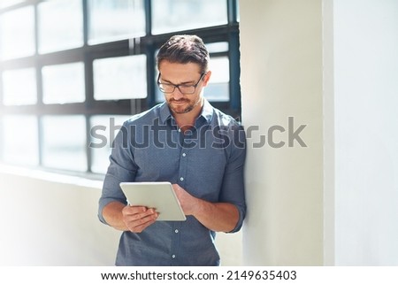 Hes a tech-savvy businessman. Cropped shot of a businessman working on his tablet in the office. Royalty-Free Stock Photo #2149635403