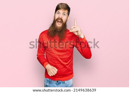 Redhead man with long beard wearing casual clothes pointing finger up with successful idea. exited and happy. number one. 