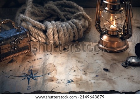 Exploration, adventure and treasure hunting concept. Vintage map, old lamp, chest, pocket watch on a wooden table. Columbus day.