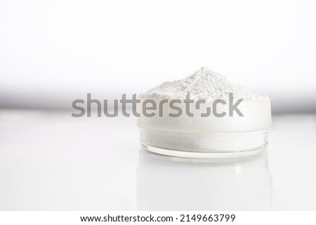 A container with zinc oxide on a white blurred background with reflection. Chemistry, health care, cosmetics production. Royalty-Free Stock Photo #2149663799