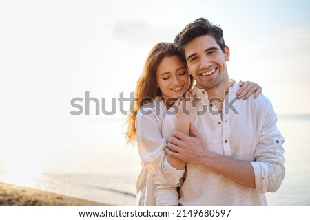 Romantic charming sunlit smiling happy young couple two friends family man woman in casual clothes hug each other at sunrise over sea beach ocean outdoor exotic seaside in summer day sunset evening