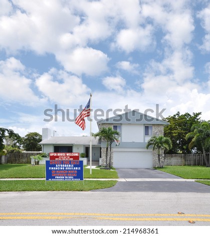 American Flag Pole Real Estate Open House Welcome sign on  front yard of Suburban Back Split style home residential neighborhood USA blue sky clouds