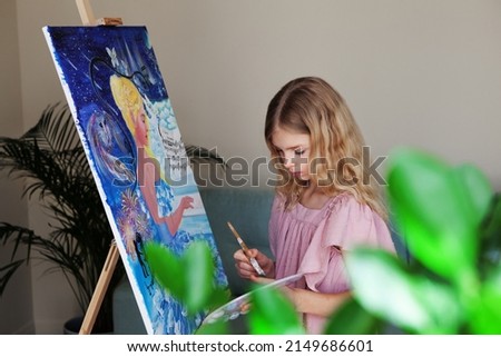 Portrait of cute teenage girl artist paints picture indoors