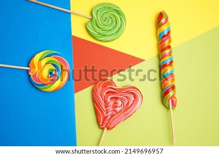 Five multi-colored lollipops of different shapes on a geometric background of different shapes.