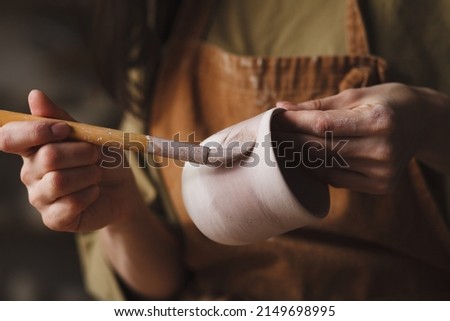 Pottery making, Female potter hands glazing clay cup Royalty-Free Stock Photo #2149698995