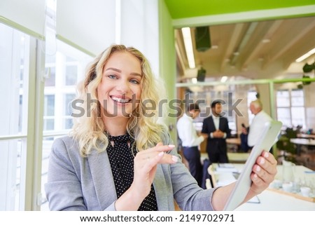 Successful business start-up woman using tablet computer with team in the background