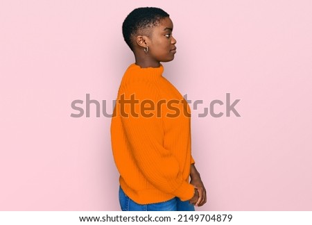 Young african american woman wearing casual clothes looking to side, relax profile pose with natural face with confident smile. 