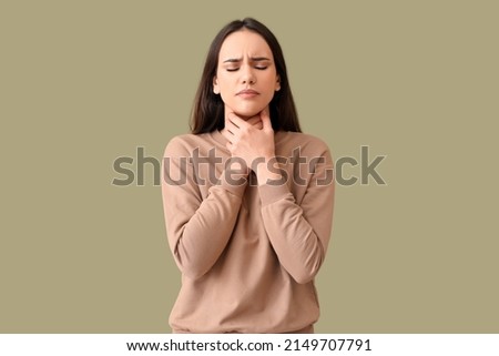Young woman suffering from sore throat on color background Royalty-Free Stock Photo #2149707791