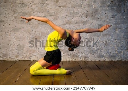 Young gymnast girl stretching and training with a red ball. Sport and healthy lifestyle concept