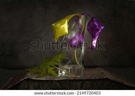 Fine art photography. Light painting. Glass vase filled with woven ribbon and dried papaya leaves                               