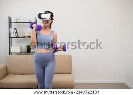 Training with dumbbell on virtual sport at home. Young asian sport woman wearing sportswear workout with virtual simulated world. Into the  future digital cyber universe. Future technology
