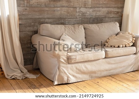 Modern Cozy living room with Comfortable beige sofa and pillows. Scandinavian interior design. Interior room wall in warm wooden tones with couch and linen curtain. Dirty sofa. Copy space. Dining room Royalty-Free Stock Photo #2149724925