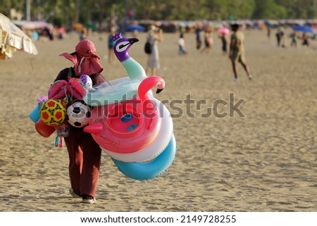A vendor sells rubber rings and soccer balls in Pattaya beach, a touristy city near Bangkok, Thailand. Thailand is accelerating the completely reopen of the country to foreign tourists amid COVID-19. Royalty-Free Stock Photo #2149728255