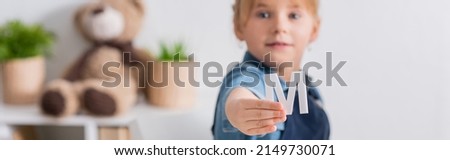 Blurred kid holding letter in classroom, banner