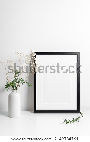 Portrait frame mockup in white minimalistic interior with flowers decorations