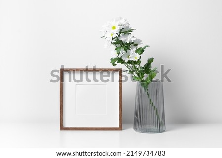 Square frame mockup in white minimalistic interior with fresh flowers in vase, copy space for artwork, print or photo presentation