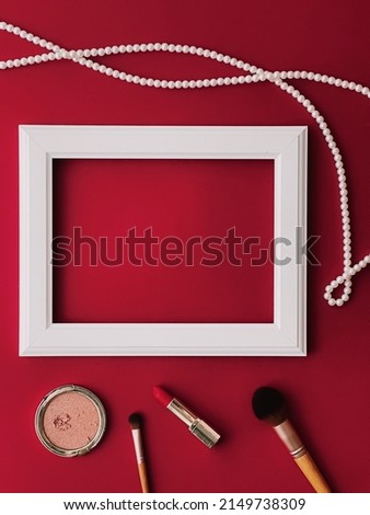 White horizontal art frame, make-up products and pearl jewellery on red background as flatlay design, artwork print or photo album concept