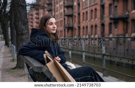 A young woman sits on a bench with a package, the concept of shopping.