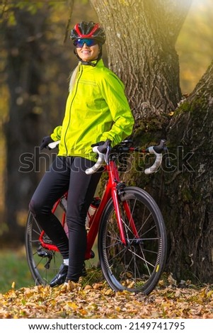 Cycling Ideas. Cute Caucasian Female Cyclist With Road Bike Posing Outdoors Near Old Tree Against Autumn Background.Vertical Image Composition