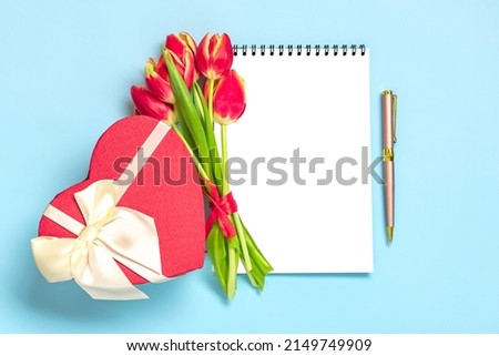 Bouquet of red tulips, gift box heart, notepad on blue background Top view Flat lay Holiday greeting card Happy moter's day, 8 March, Valentine's day, Easter concept Copy space Mock up