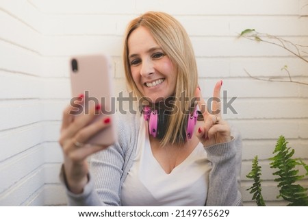Image of happy nice woman in casual clothing smiling and using cellphone in terrace at home