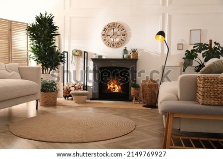 Stylish living room interior with electric fireplace, comfortable sofas and beautiful decor elements