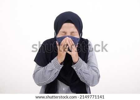 Young Asian Muslim woman wearing a mask and who is sick is covering her nose, coughing or sneezing because she has flu. Cold and fever concept with copy space, isolated in white background