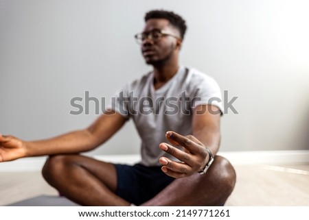 One young handsome man meditating in the living room. Handsome young man meditating in the living room. Shot of a young man meditating at home