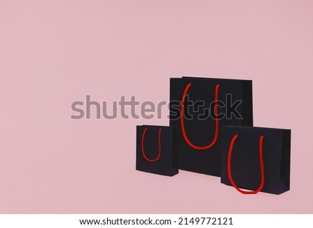 Shopping bags. Template with copy space. Three paper packs with red handles on pink backdrop
