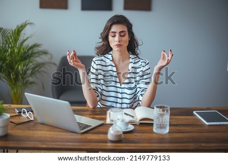 Calm female executive meditating taking break at work for mental balance, mindful businesswoman feeling relief and no stress doing yoga at work ignoring avoiding stressful job and paperwork in office Royalty-Free Stock Photo #2149779133