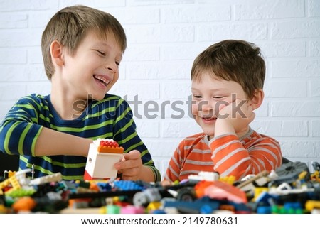 Two boys sit down at the table and assemble the designer. Children laugh, are joyful, they have fun doing things together, playing and building from details. Royalty-Free Stock Photo #2149780631