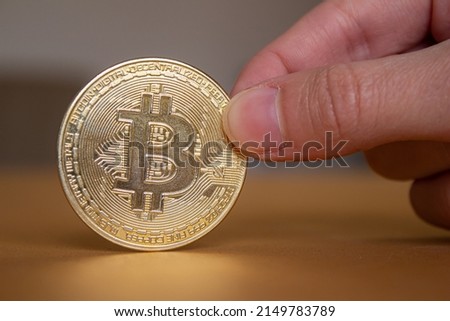 Hand holding virtual currency bitcoin. Closeup photo of golden bitcoin.