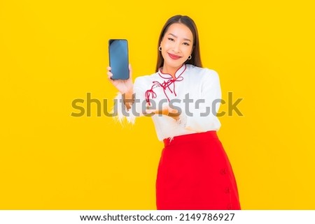 Portrait beautiful young asian woman with smart mobile phone on yellow background