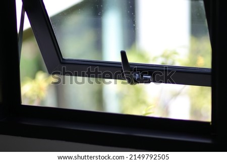 Awning window frame open, black metal detail with nature view and free space. Louver glass texture for house decor, building, real estate, property, living, hotel. Close up Aluminum casement. Royalty-Free Stock Photo #2149792505