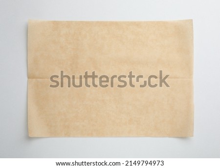 Sheet of brown baking paper on white background, top view