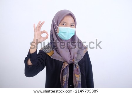 Muslim woman wearing a mask with OK hand gesture