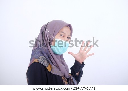 portrait of a Muslim woman in a mask with a confident gesture looking at the camera and say hello