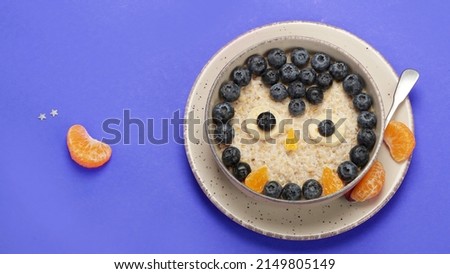 Oatmeal for kids on coloutfull background. Healthy breakfast idea. Playful lunch. Top view, flat lay, copy space