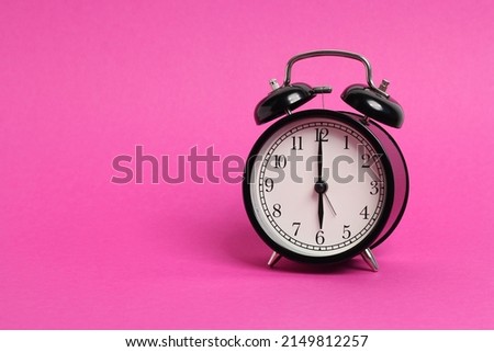 vintage old black alarm clock on pink background