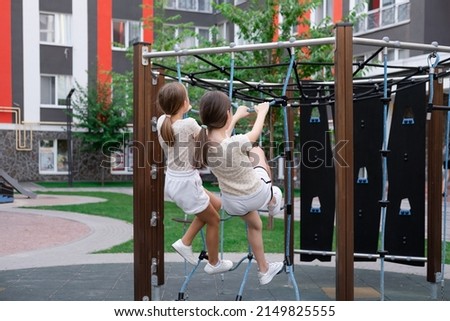 two pretty teen girls playing on a modern playground in identical clothes. sister, bffs. sisterhood, friendship