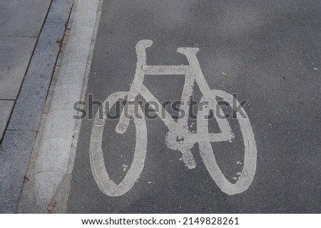 White paint road markings of a bicycle symbol painted on black tarmac road surface. Safety warning logo sign for cyclists. 