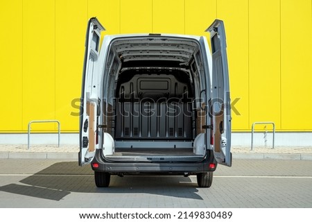 Empty van with open doors in front of a yellow wall Royalty-Free Stock Photo #2149830489