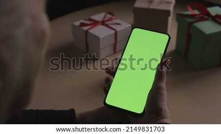 old female hands holding smartphone with green screen and celebrating holiday chatting with family, wide photo