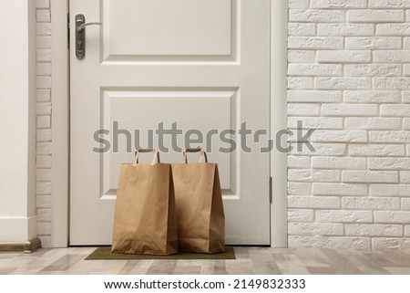 Paper bags on door mat near entrance, space for text Royalty-Free Stock Photo #2149832333